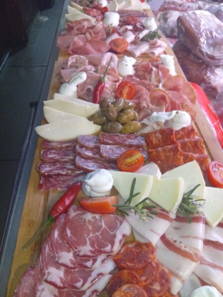 Clienti al banco di una bottega che degustano prodotti tipici calabresi